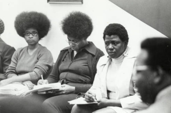 Black Women seated filling out forms.