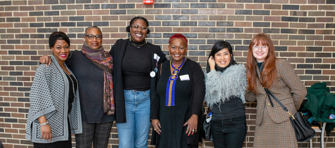 GWS and BLST staff members and professors (l to r: Melissa Portis, Dr. Lynette Jackson, Briana Hanny, Dr. Manoucheka Celeste, Dr. Akemi Nishida, and Leeann Ream) stand side-by-side in front of a brick wall, smiling at the camera at the GWS 50th Anniversary Celebration.