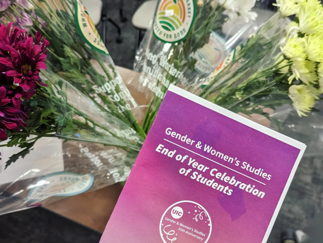 The GWS End of Year Celebration of Students program booklet lays atop bunches of purple, white, and yellow mums. The program booklet has shades of pink and purples for the background, with white text on the cover.