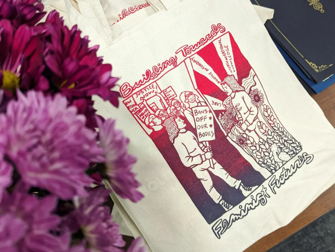 Tote bag with Feminist Futures print design by GWS alum and artist Monica Trinidad.